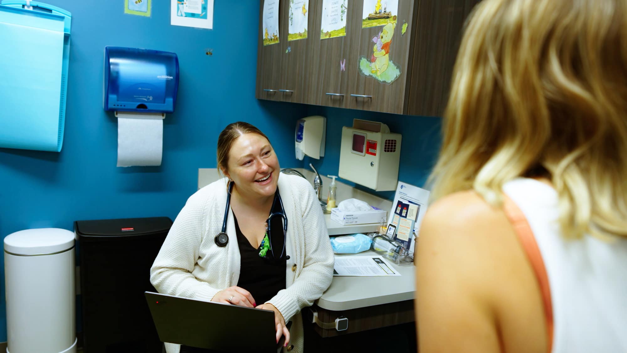 Care team member speaking with an adult in an exam room