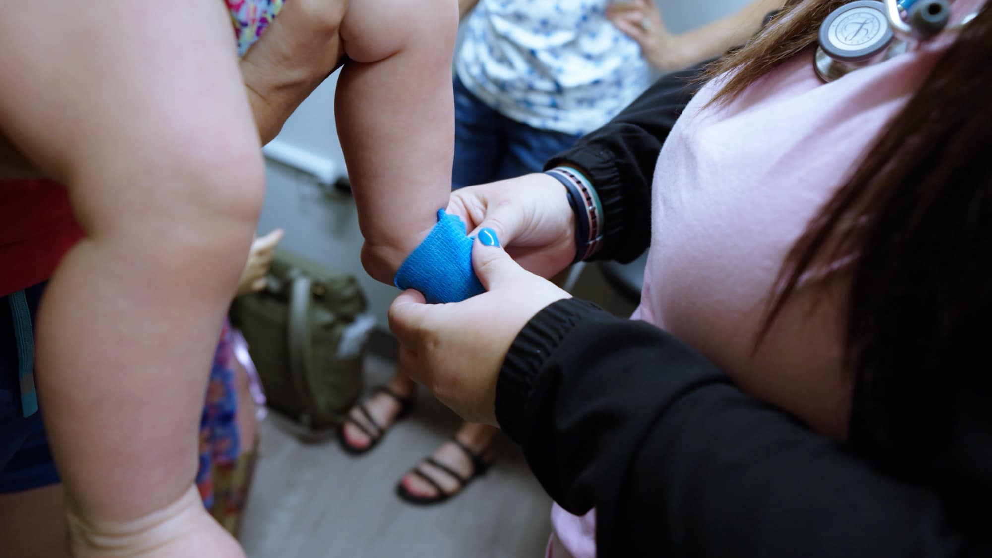 Care team member wrapping a child’s limb with a blue bandage