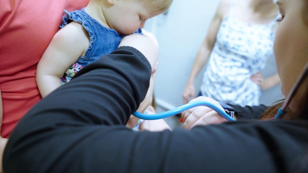 Care team member examining an infant with a stethoscope