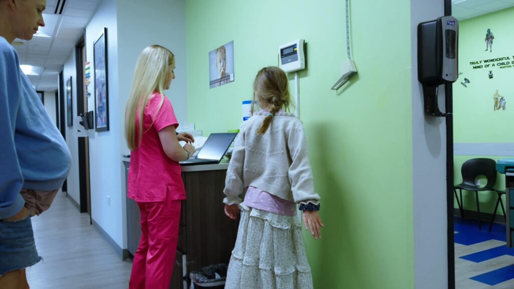 Staff member assisting a child at a clinical workstation