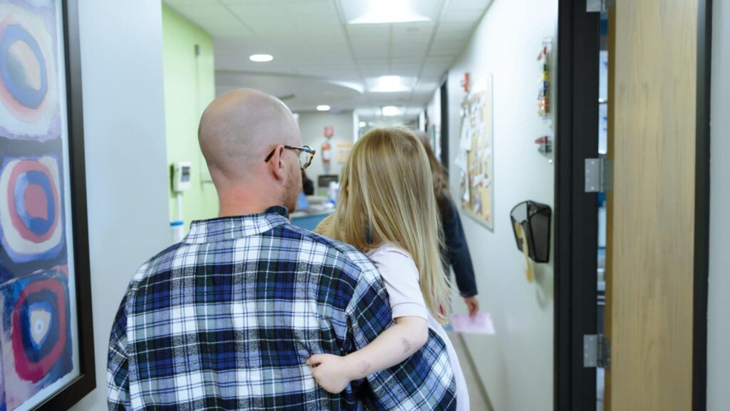 Adult carrying a child through the Sapphire Pediatrics hallway