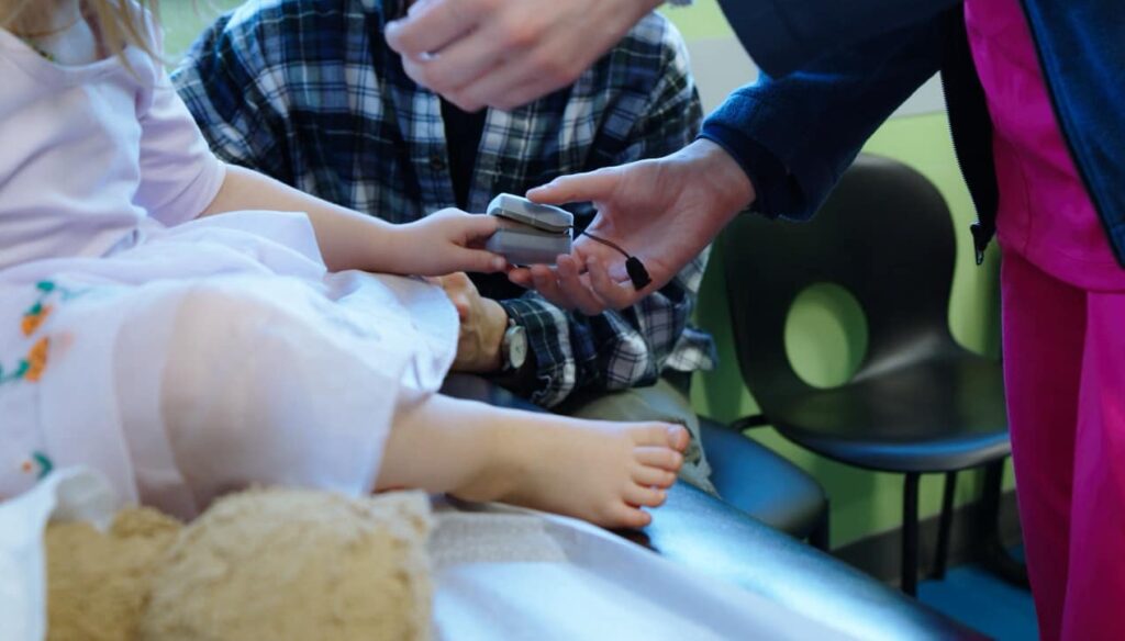 Care team member placing a finger pulse oximeter on a child