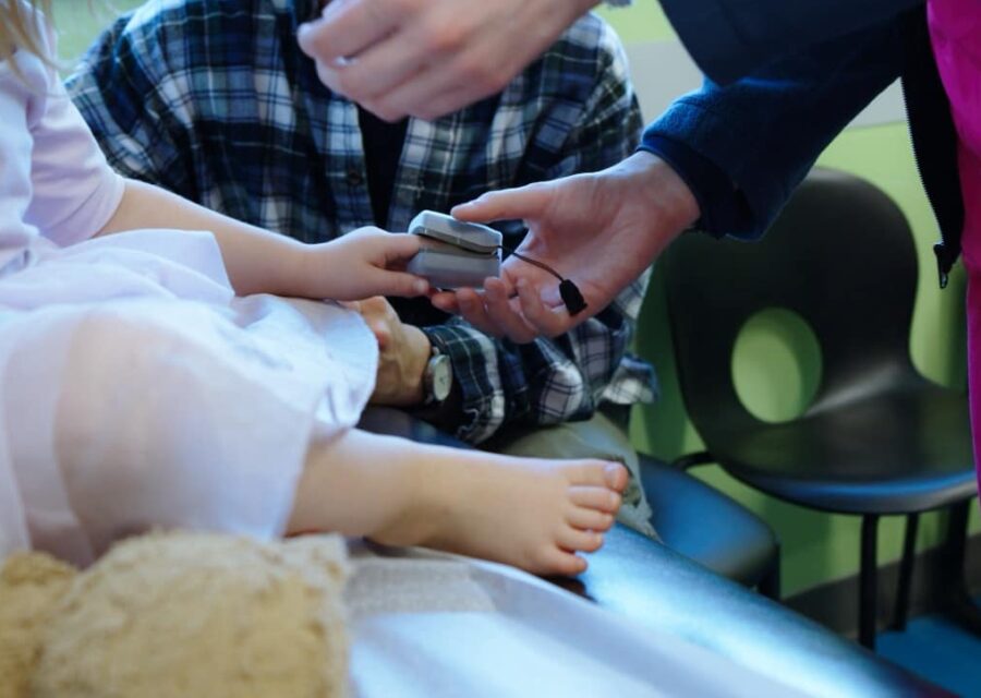 Care team member placing a finger pulse oximeter on a child