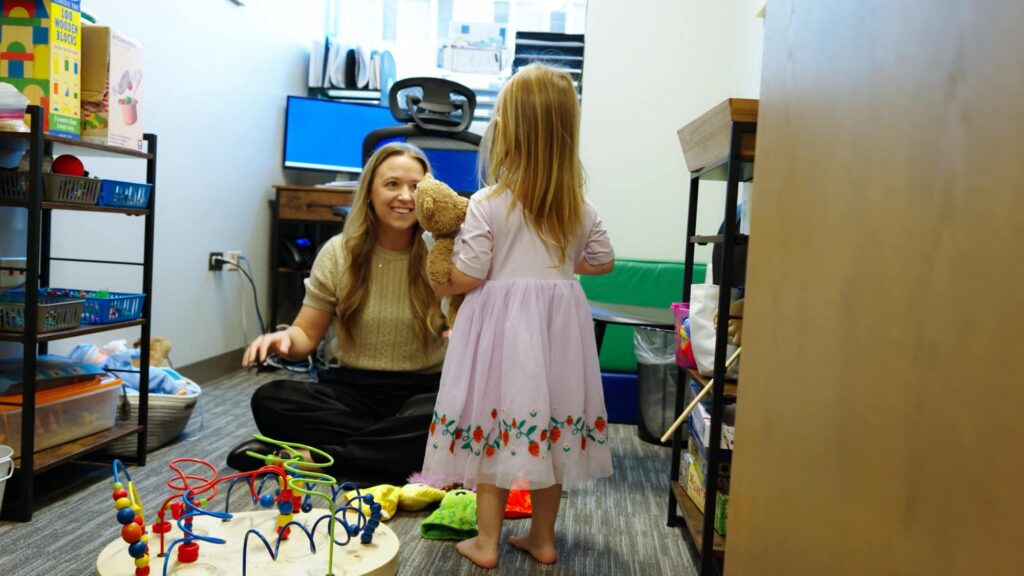 Care team member and child participating in floor play