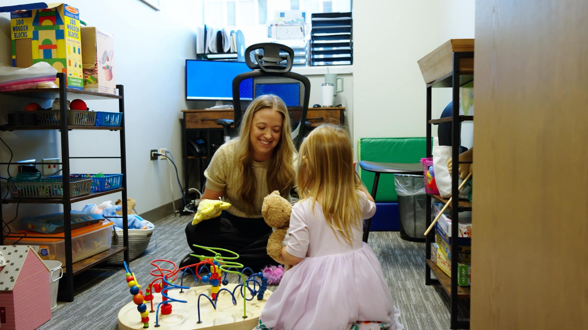 Care team member using a yellow hand puppet with a child