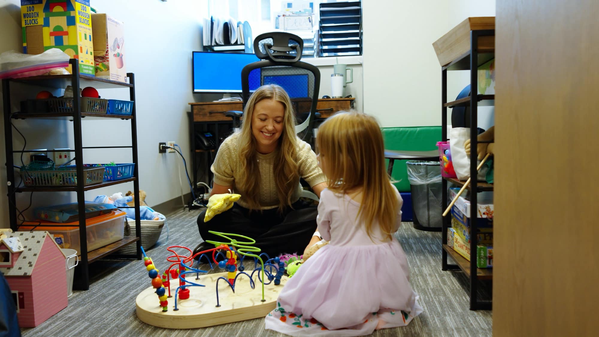 Care team member using a yellow hand puppet with a child