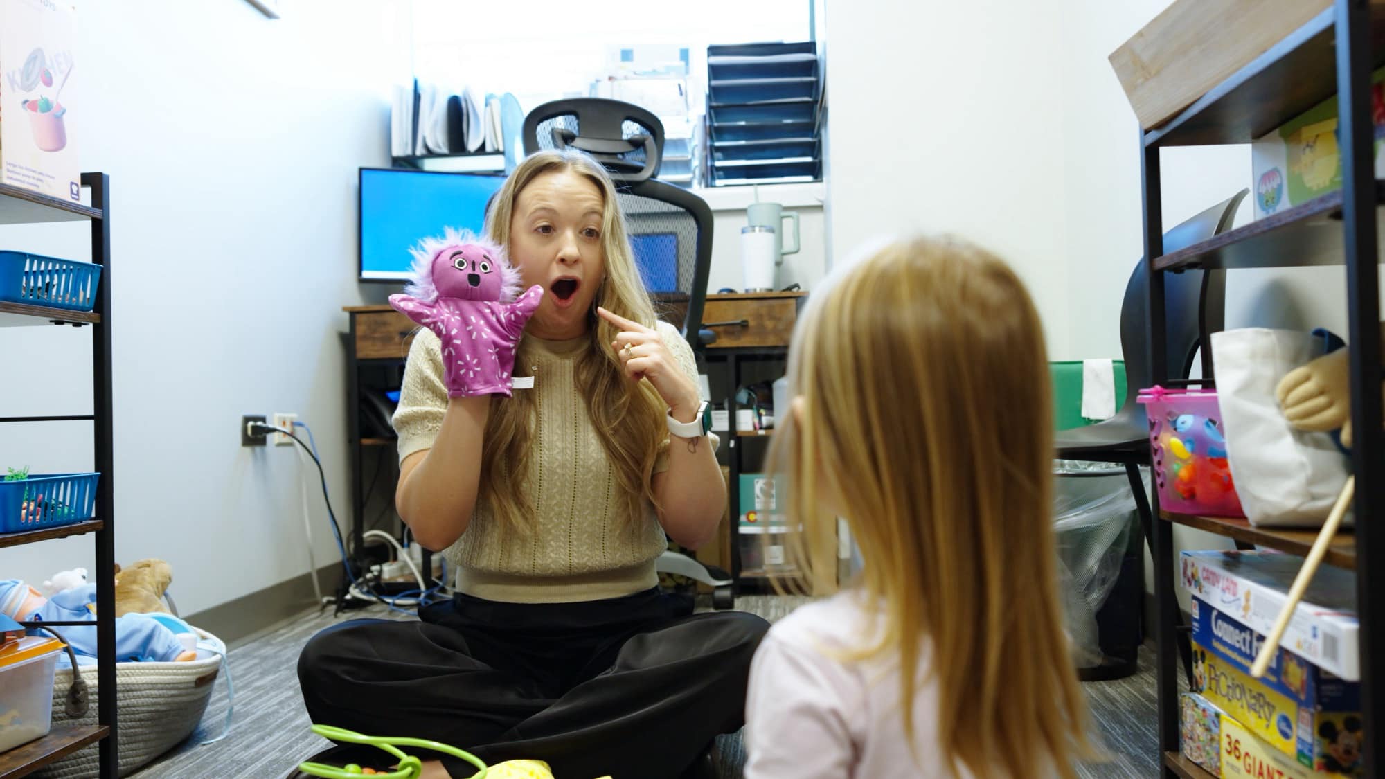 Care team member using a purple hand puppet with a child